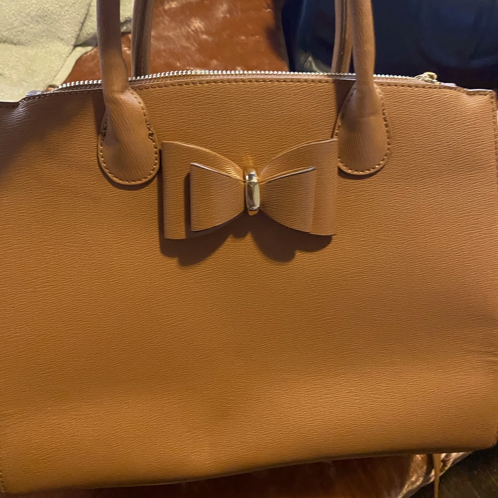 Tan handbag with bow and gold tone hardware detail.